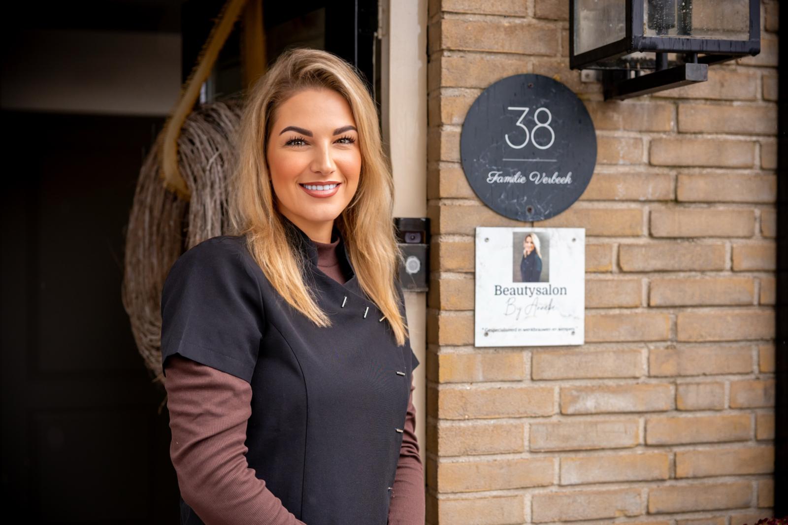 Anneke bij het naambord van de salon